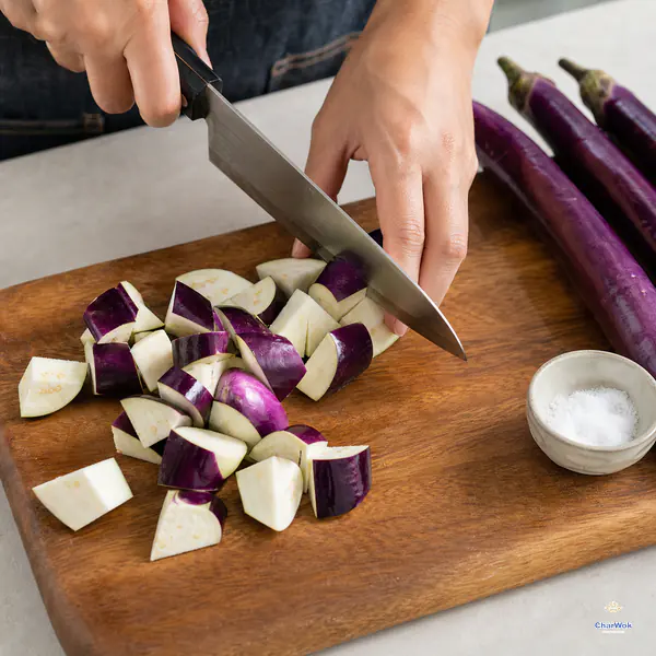 Slender purple Chinese eggplants are cut into irregular bite-size chunks with their skin left on and fresh pale interiors exposed