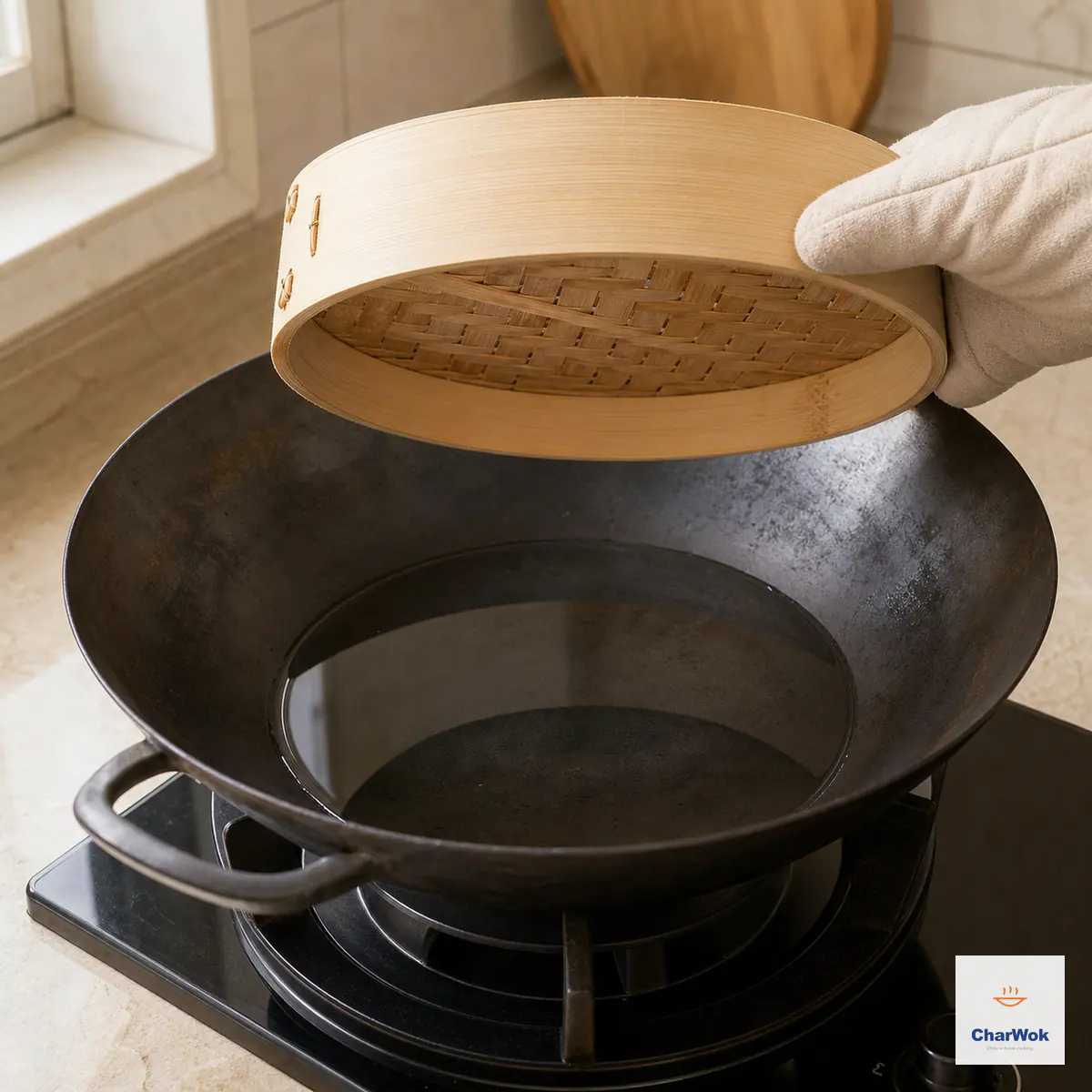 An empty bamboo basket held above a black wok with shallow clear water, leaving a visible dry air gap between the basket base and water surface