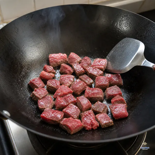 高温碳钢锅飘出一缕白烟,薄油里的生牛肉粒铺成不拥挤单层,贴锅底面开始褐变而锅铲尚未翻动