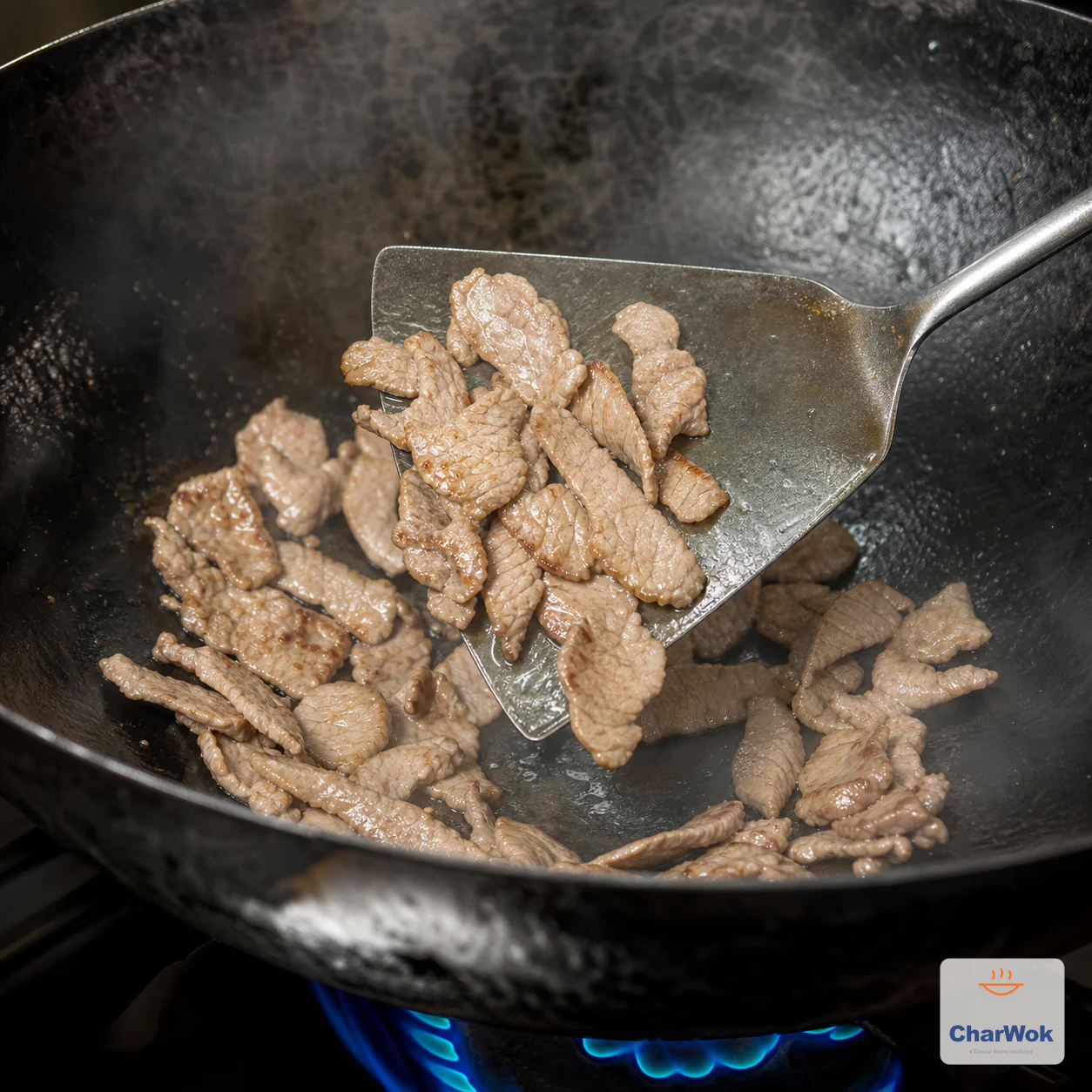Beef slices in a hot carbon-steel wok have just turned opaque and are being lifted out
