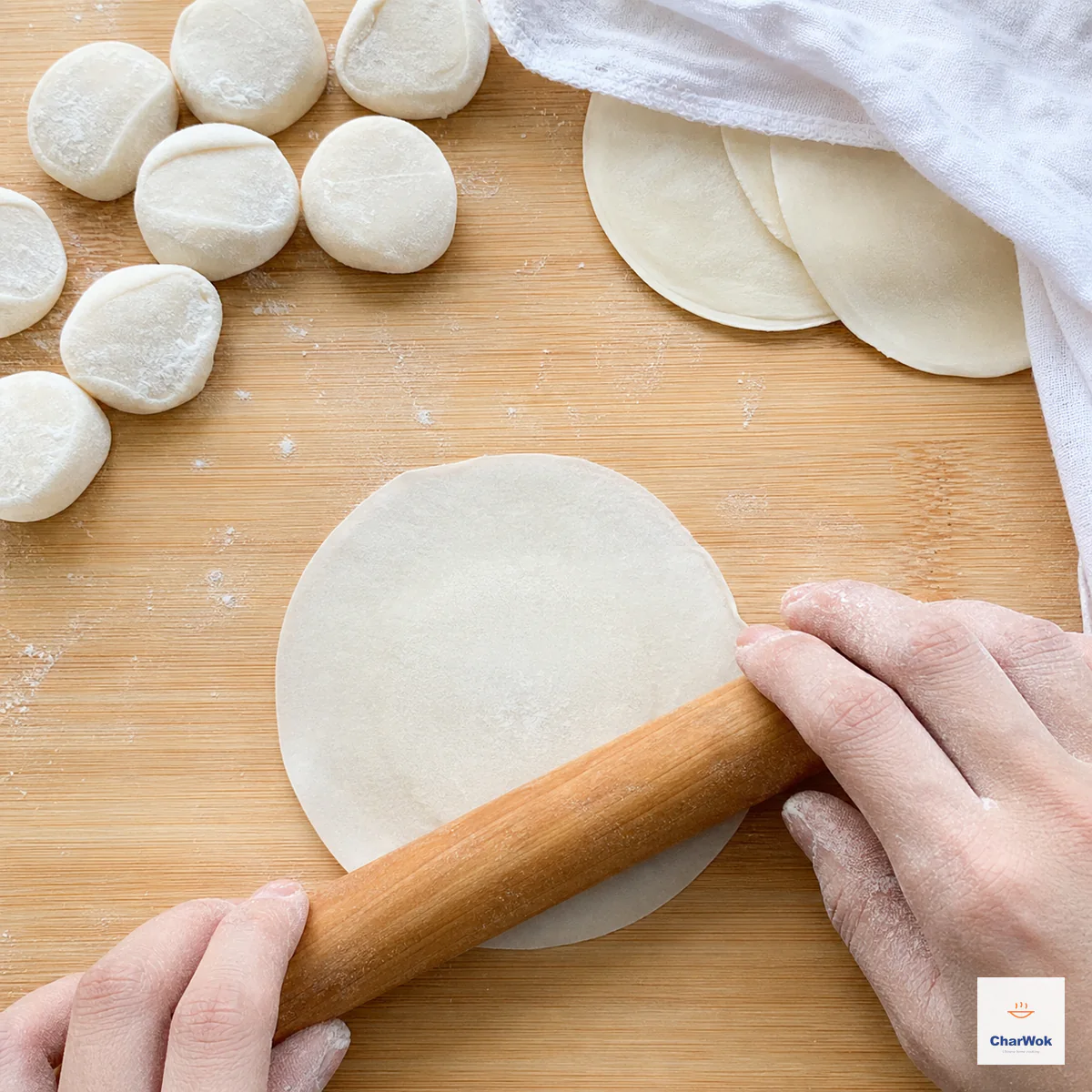 A small rolling pin forms a round dumpling wrapper with a thicker opaque center and evenly thin edges while dough pieces and finished rounds stay covered