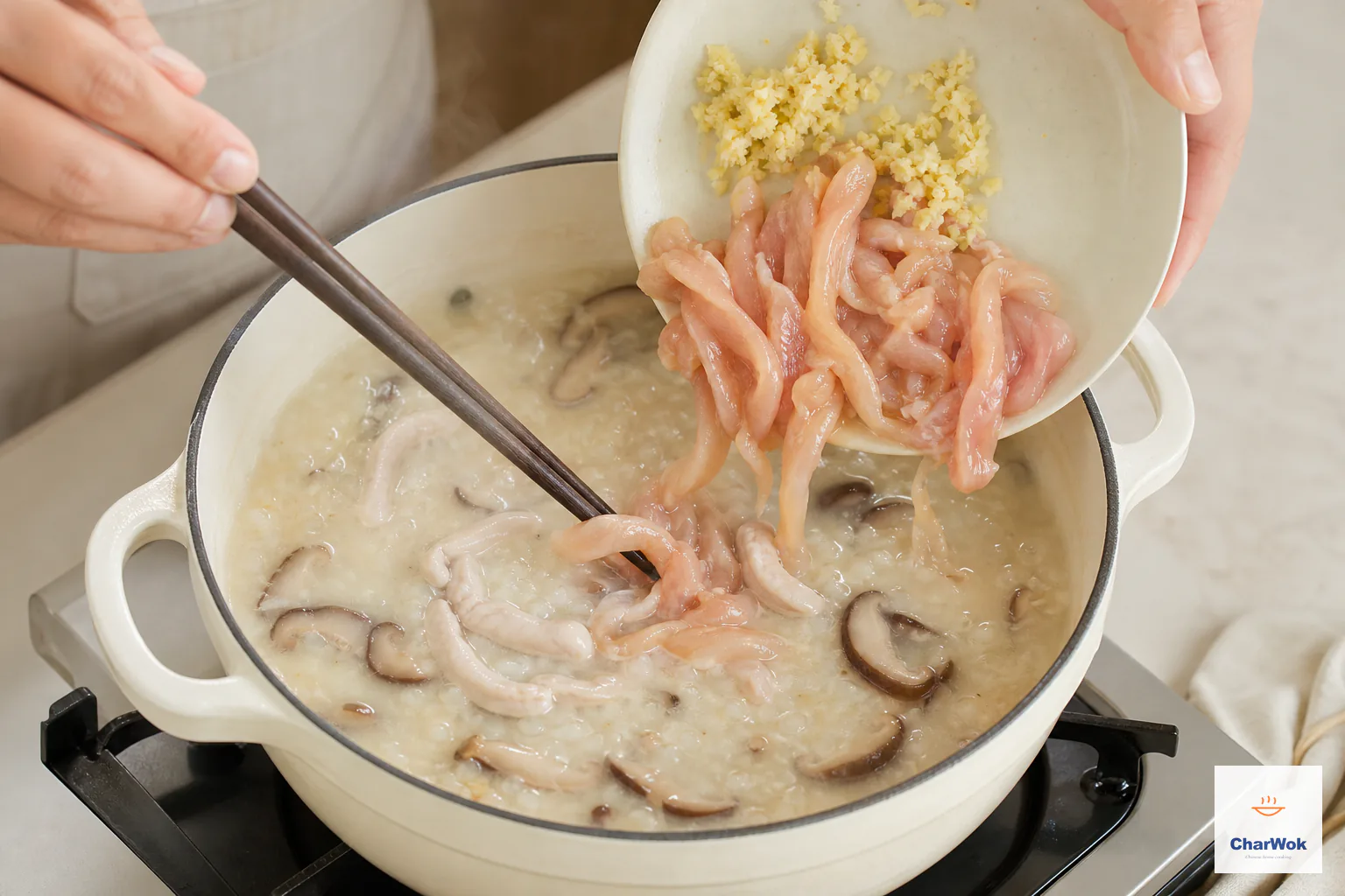 Thin marinated chicken strips and minced ginger enter creamy shiitake congee while chopsticks separate the strips so they heat evenly