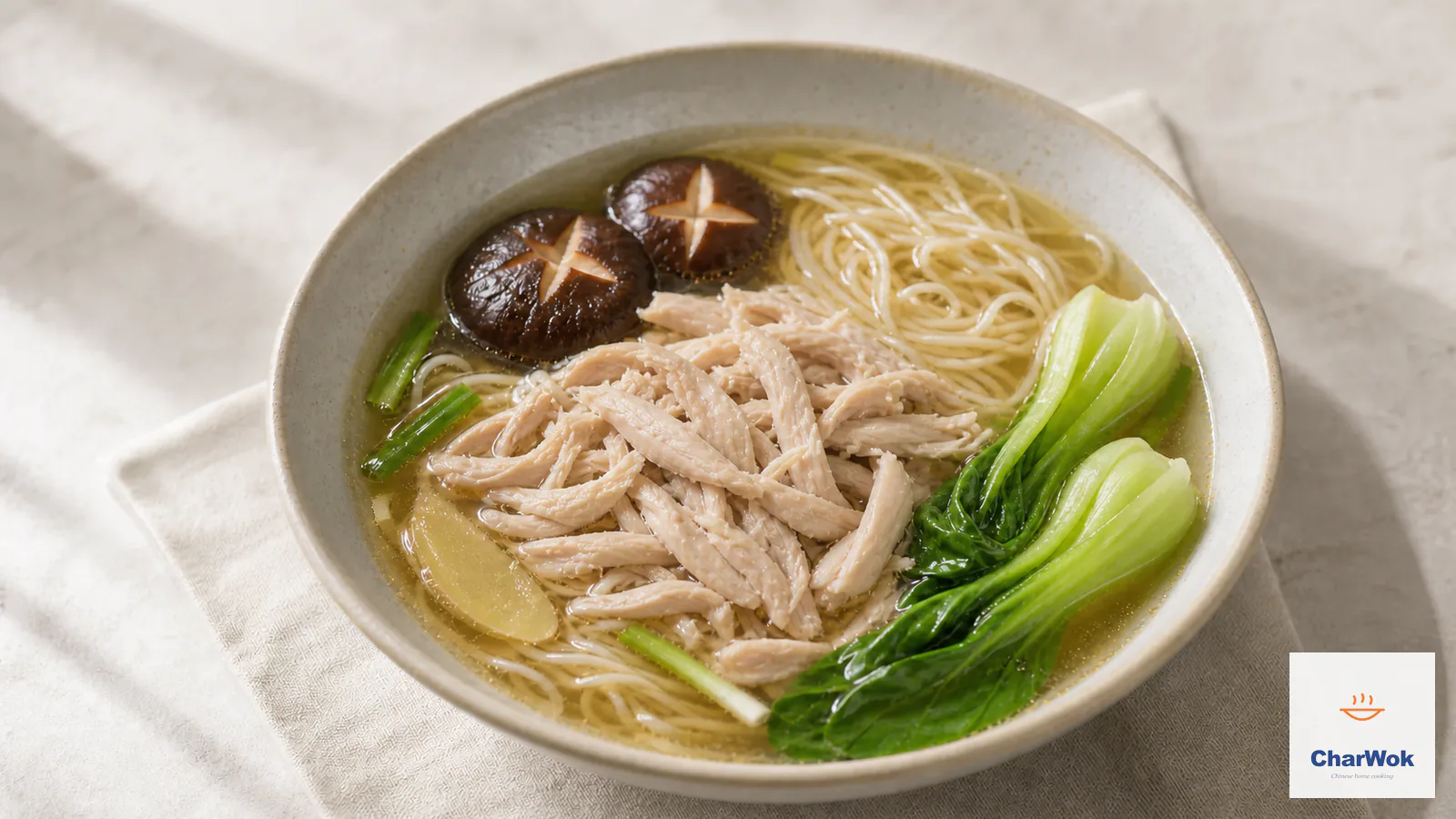 Clear Chinese chicken noodle soup with hand-shredded chicken, shiitake, thin noodles, and baby bok choy