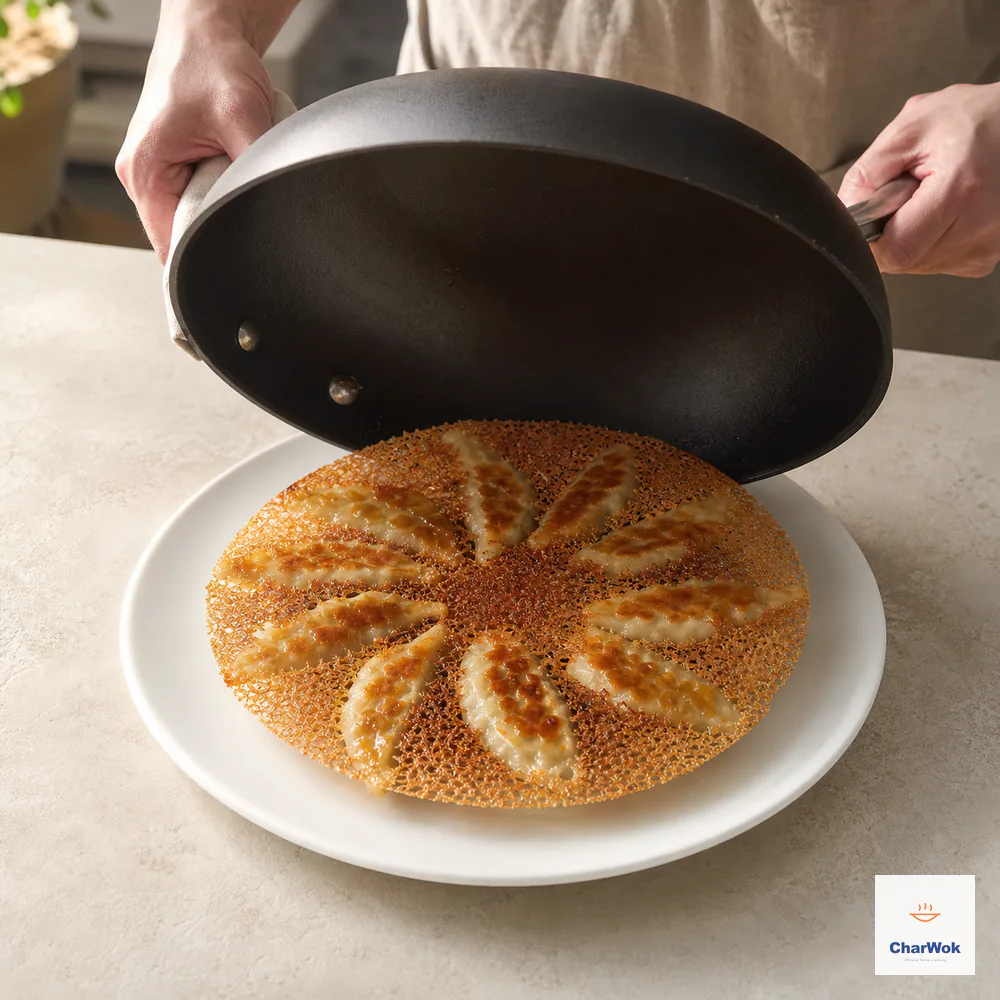 Hands lift an inverted nonstick skillet from a white plate, revealing chicken potstickers attached to one intact circular crisp skirt with the lacy side upward