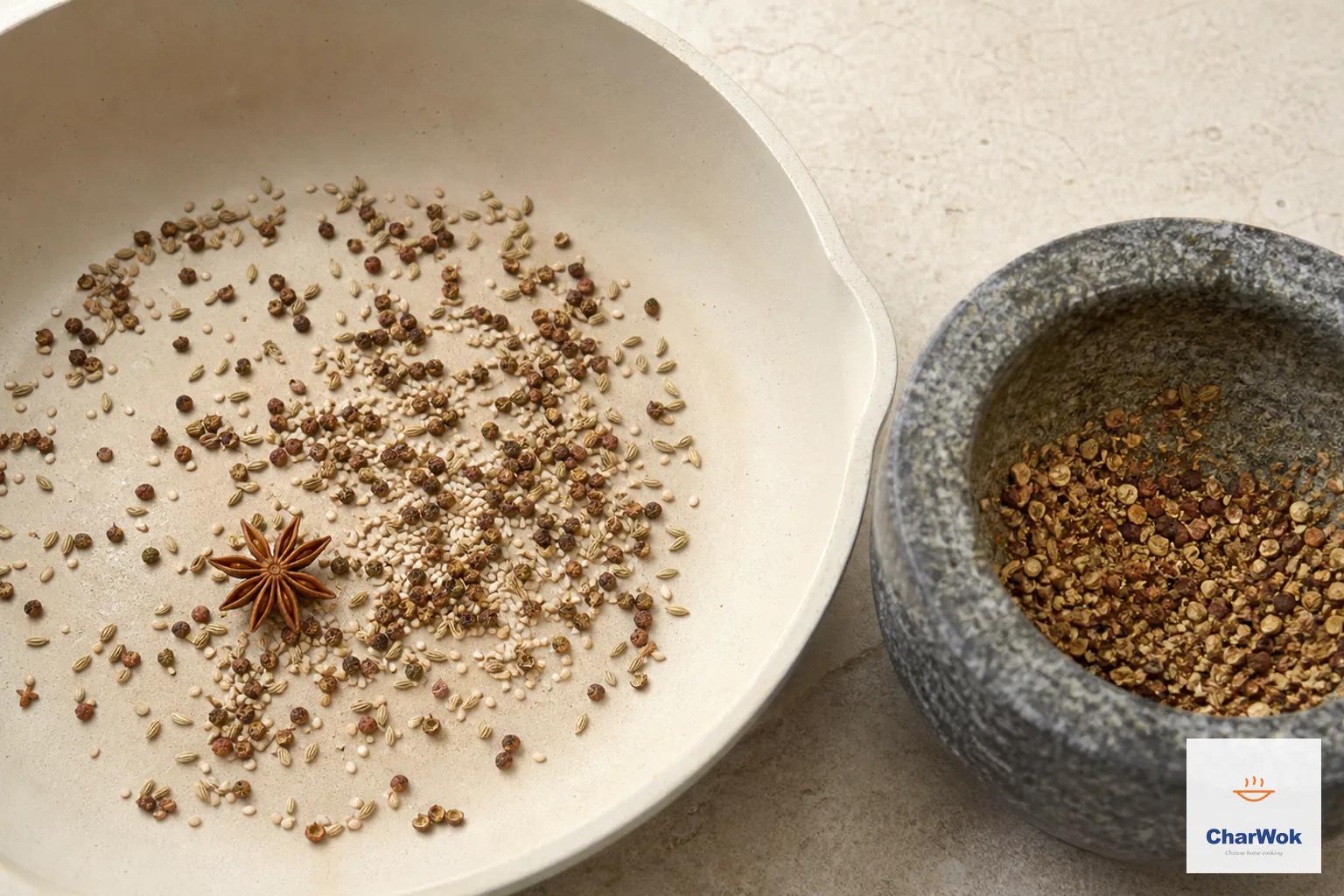 A dry skillet holds toasted Sichuan peppercorns, fennel, sesame and star anise beside a mortar of visibly coarse cracked spice and salt