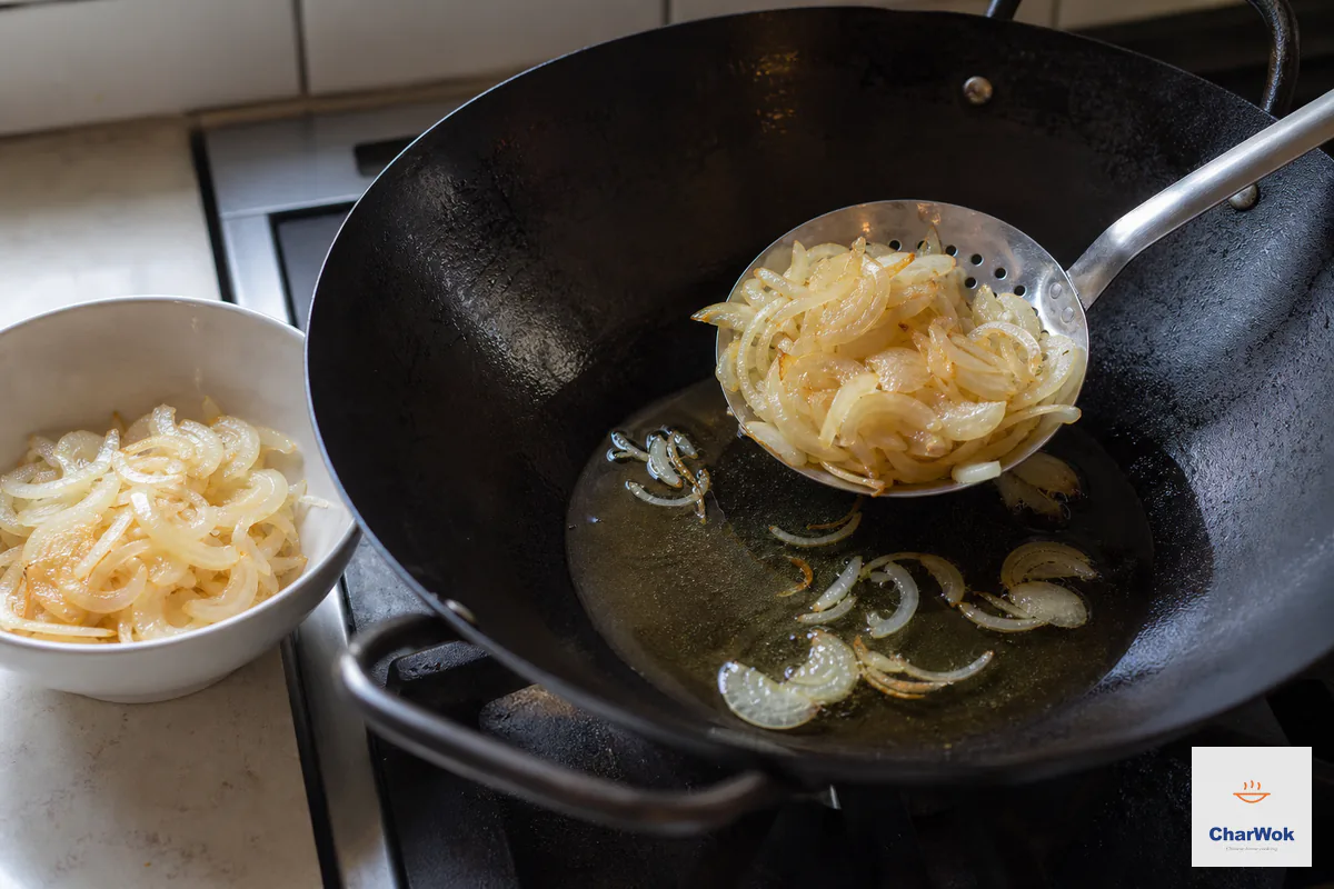 Golden onion slices are lifted from gently bubbling neutral oil with a wire skimmer before they darken