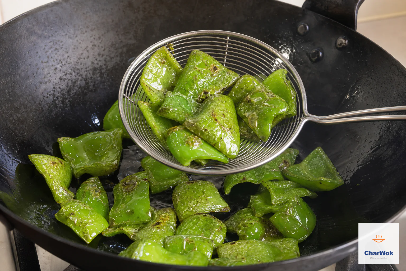 Bright green pepper chunks with a few blistered freckles remain firm as a wire skimmer lifts them from the wok