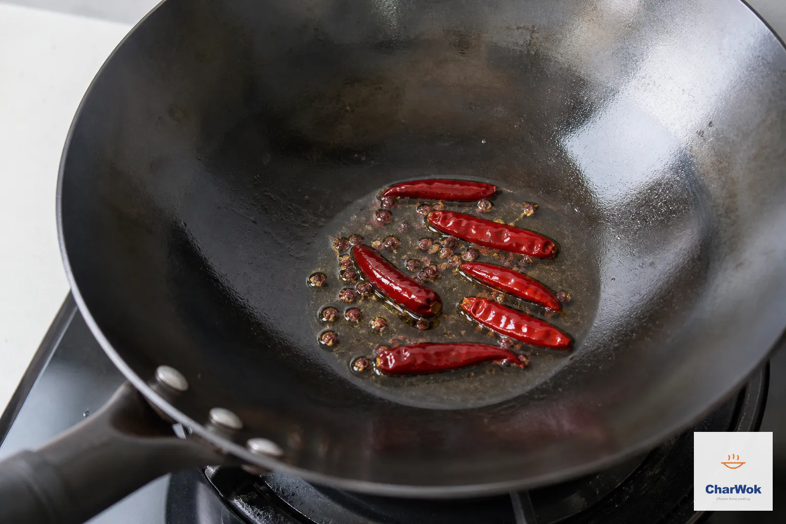 Six dried red chilies and whole Sichuan peppercorn bloom in a thin film of hot oil without any blackened spices