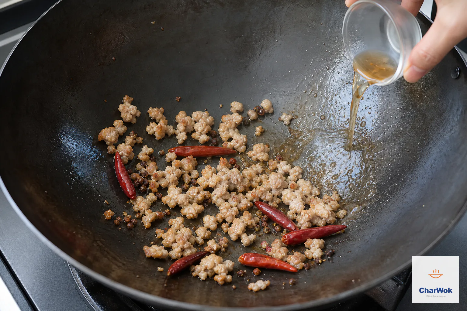 Small minced-pork crumbles with browned edges cook among six dried chilies while Shaoxing wine is poured against the exposed hot wok