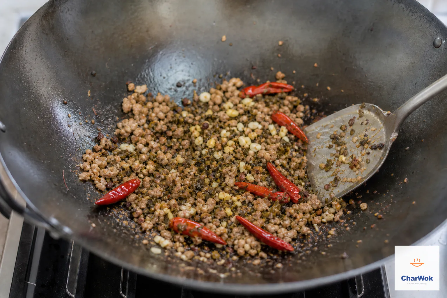 Minced garlic, ginger and dark olive-brown ya cai are folded into browned pork, peppercorn and six dried chilies with no pooled sauce