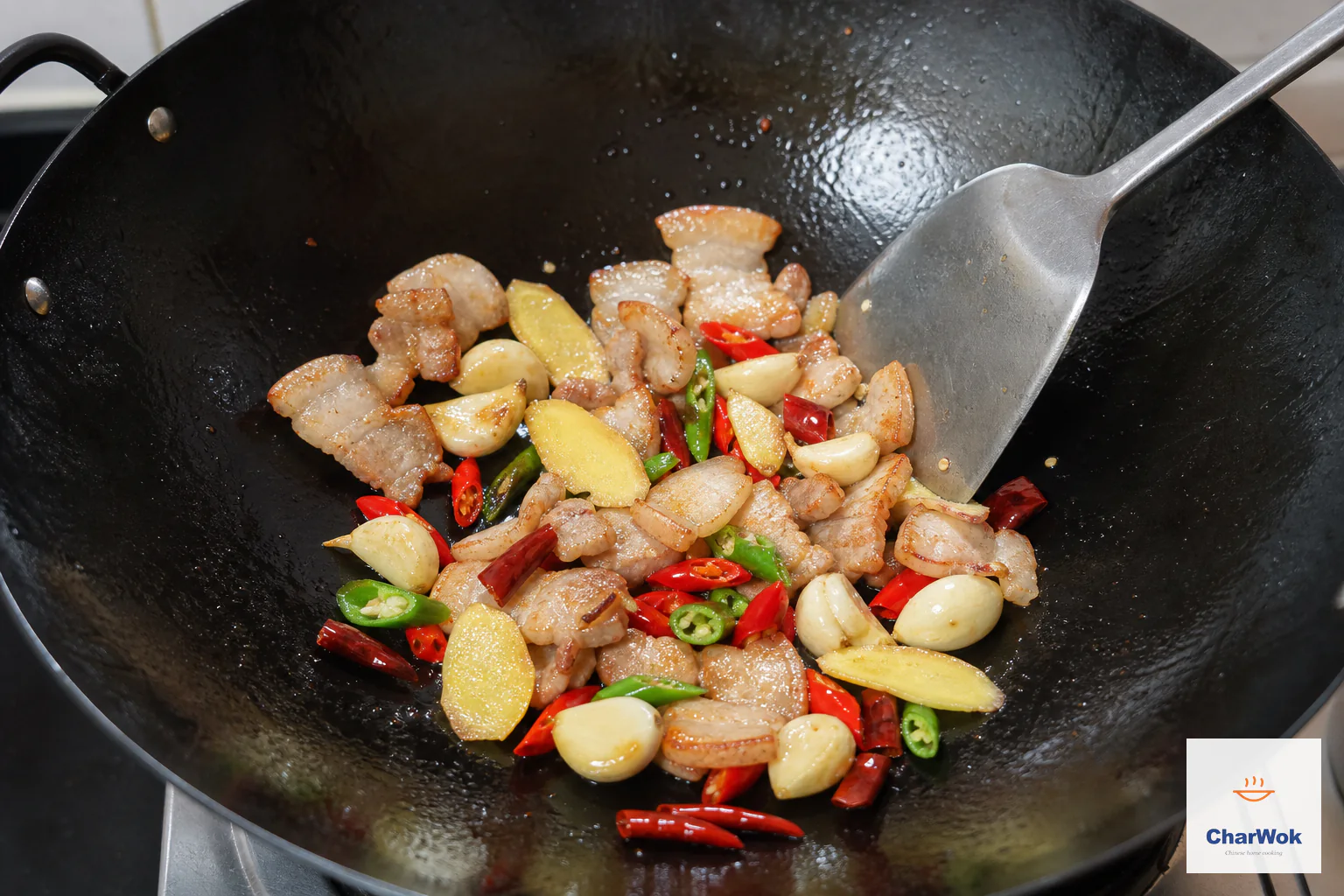 Smashed garlic, four ginger slices, fresh red and green chili and dried chili segments toss with lightly golden pork belly in a carbon-steel wok