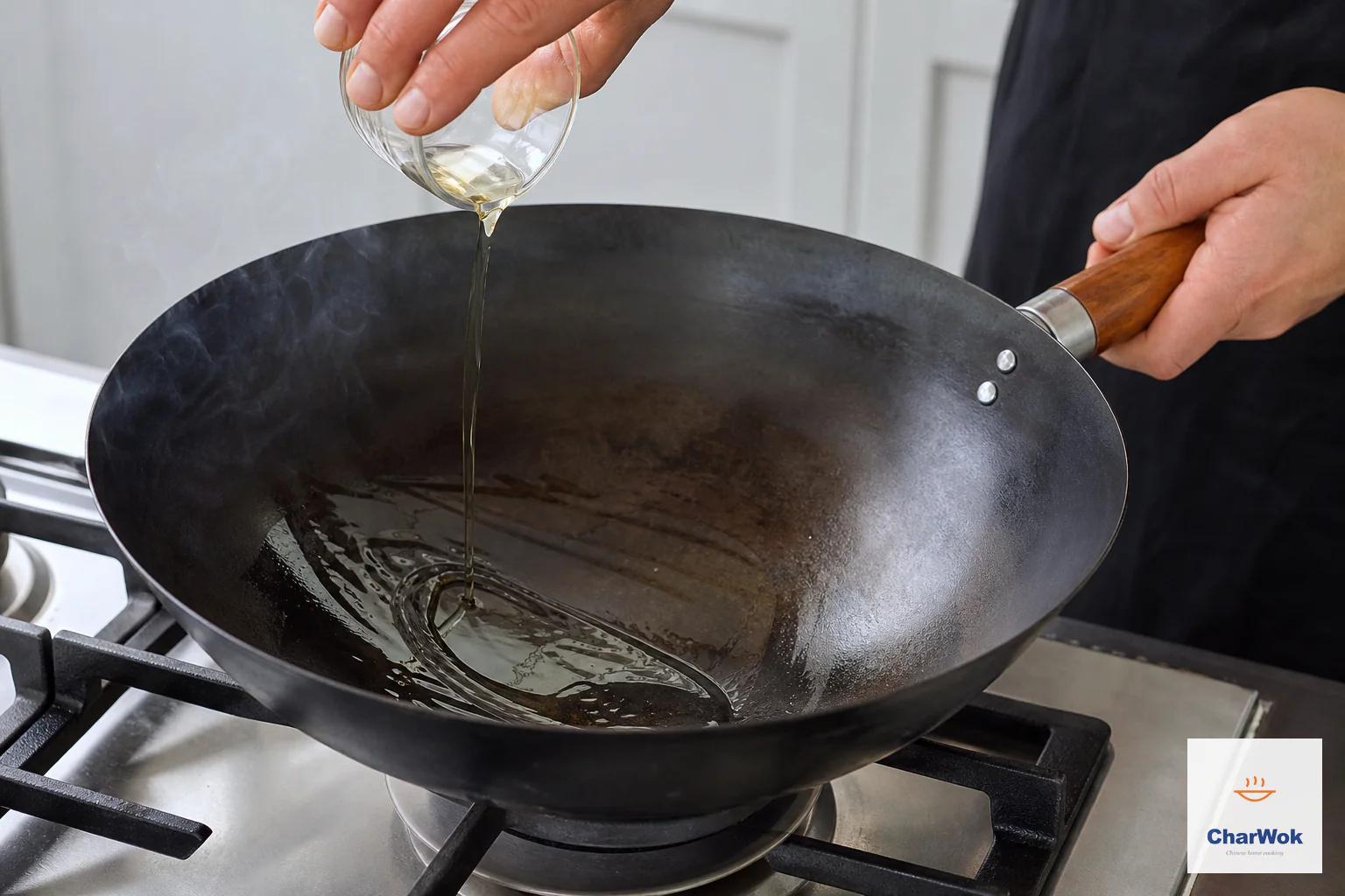 A restrained ribbon of neutral oil pours into a faintly smoking seasoned carbon-steel wok as the wooden handle is tilted