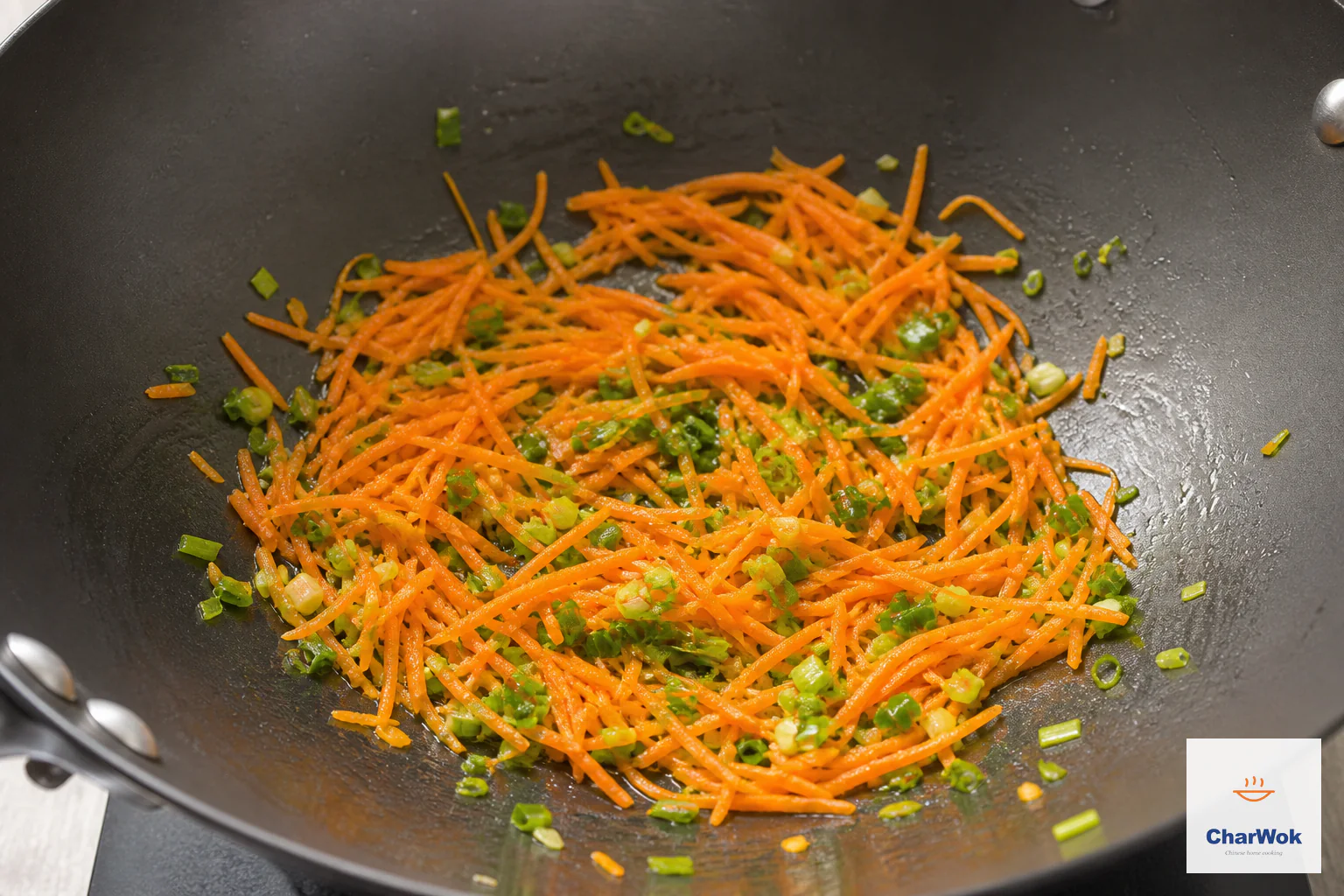 Bright grated carrot and chopped scallion soften in a small lightly oiled wok without browning