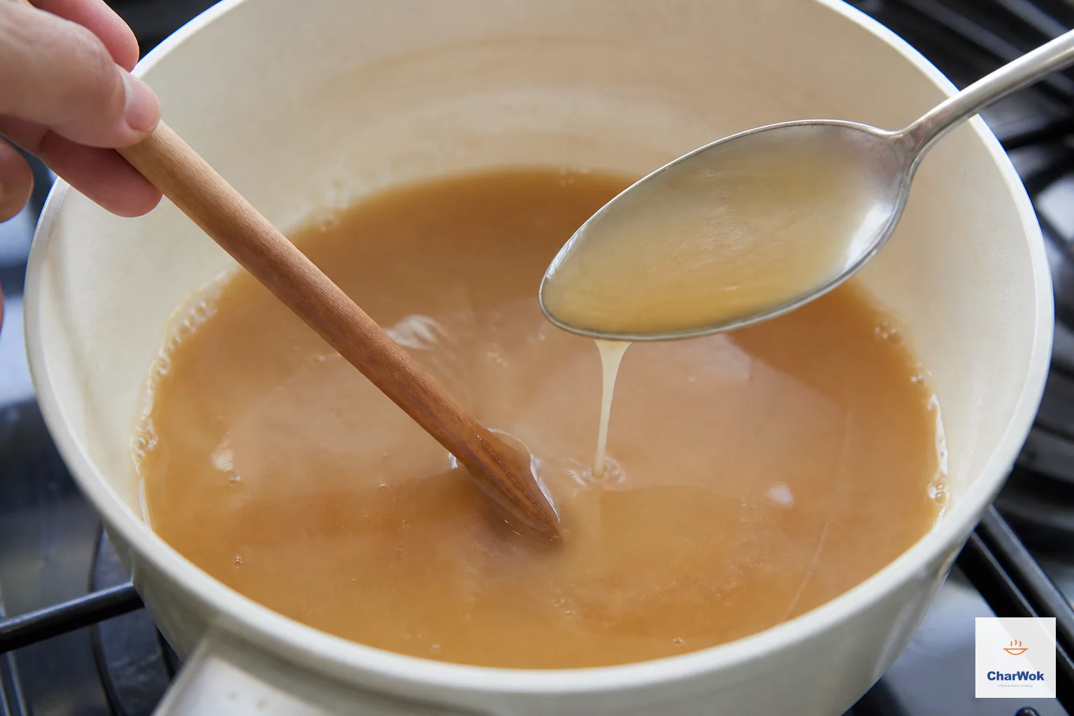 Light-brown gravy at a gentle boil leaves a thin translucent coat on the back of a lifted metal spoon