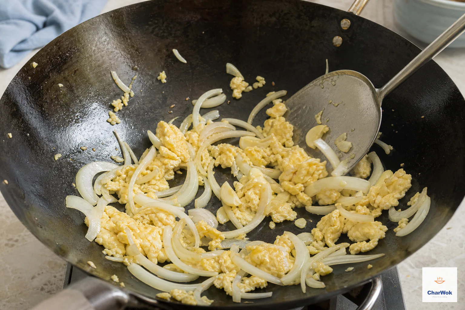 Sliced onion and crushed garlic are tossed with golden egg curds while the onion edges remain pale and crisp