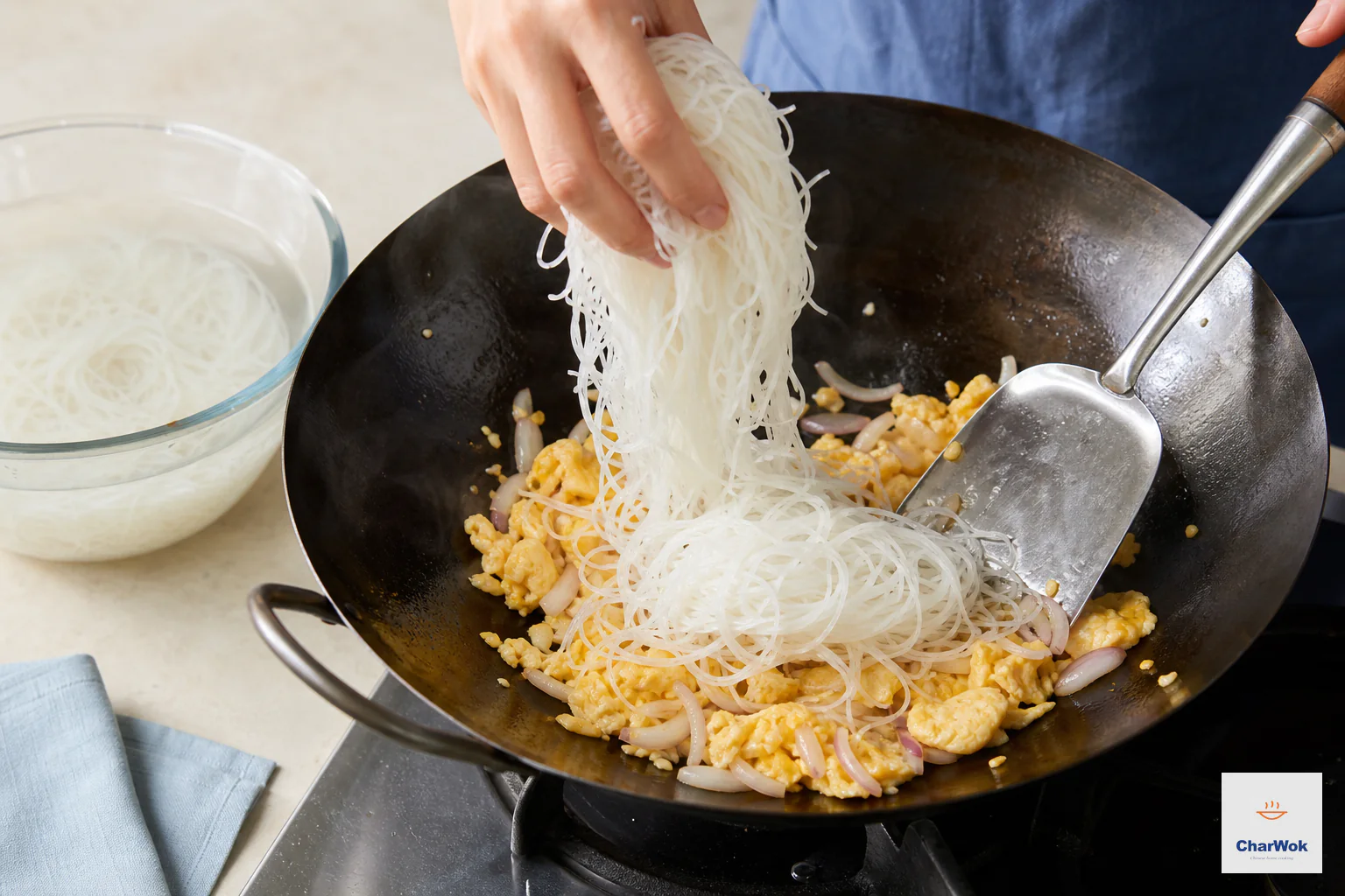 Moist pale thin rice noodles lift straight from a cold-water bowl into a wok with egg, onion and garlic