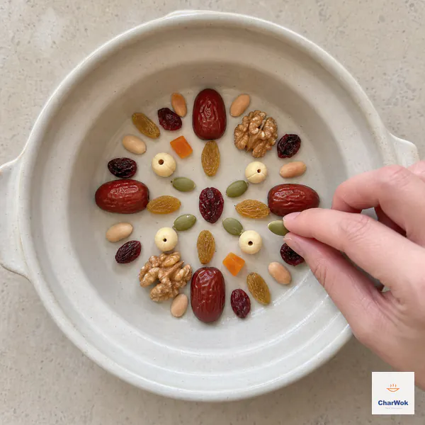 Jujubes, raisins, cranberries, apricot, walnuts, pumpkin seeds, peanuts, and lotus seeds form one flat radial pattern on the oiled bowl bottom
