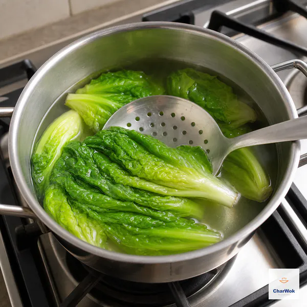 A slotted spoon submerges vivid-green lettuce in just-boiled water over a visibly unlit stove burner