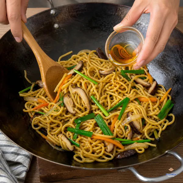 Fresh Chinese chive sections and a small drizzle of toasted sesame oil are folded into glossy longevity noodles off the heat