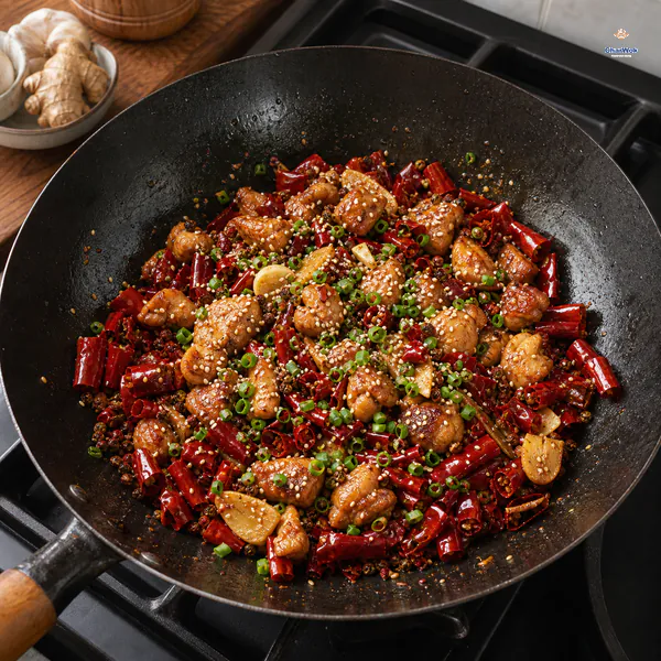 Deep-golden chicken is tossed with glossy red chili halves, peppercorns, ginger and garlic, then finished with sesame and chopped scallion in an unlit wok
