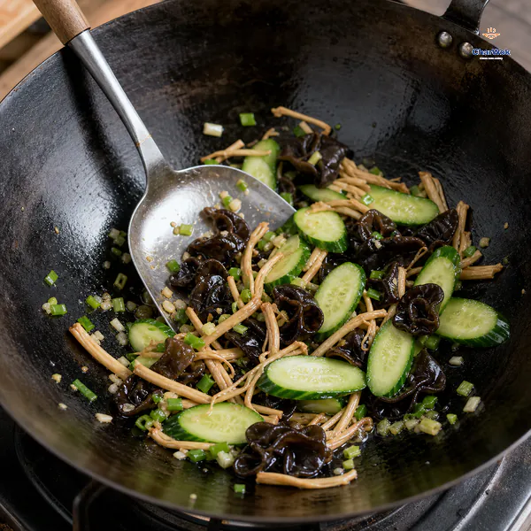 Bright diagonal cucumber slices, black wood ear, tan lily buds, chopped scallion and minced ginger are tossed in a lightly oiled wok