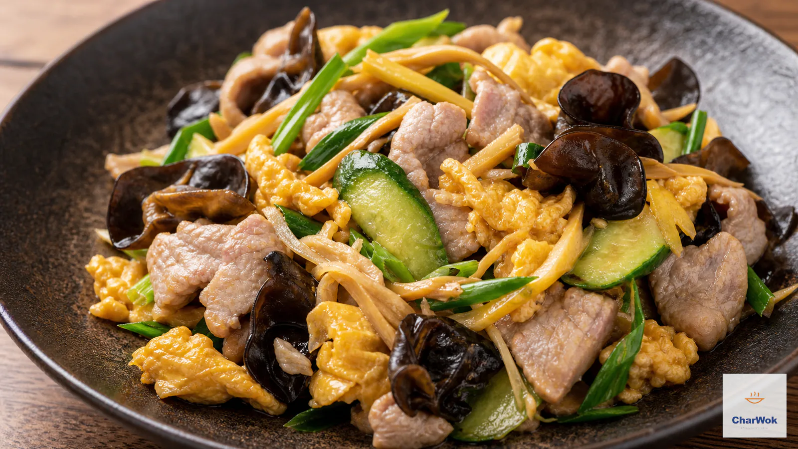 Tender pale pork slices, glossy golden egg, black wood ear, lily buds, cucumber and scallion served on a dark platter