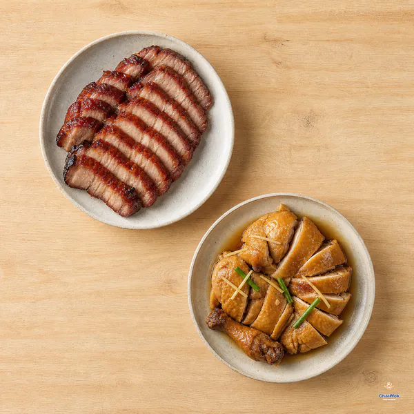 A full plate of sliced red-brown glazed char siu sits beside amber soy sauce chicken cut into even cooked pieces