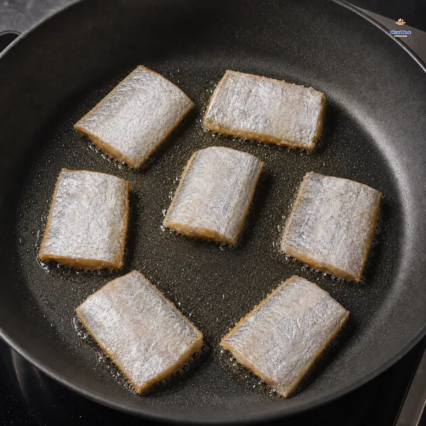 Exactly seven belt-fish sections fry in one spaced single layer with untouched silver tops and thin golden edges