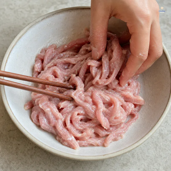 Thin raw pork tenderloin slivers are kneaded until the velveting liquid is absorbed and a milky sticky film clings without pooling