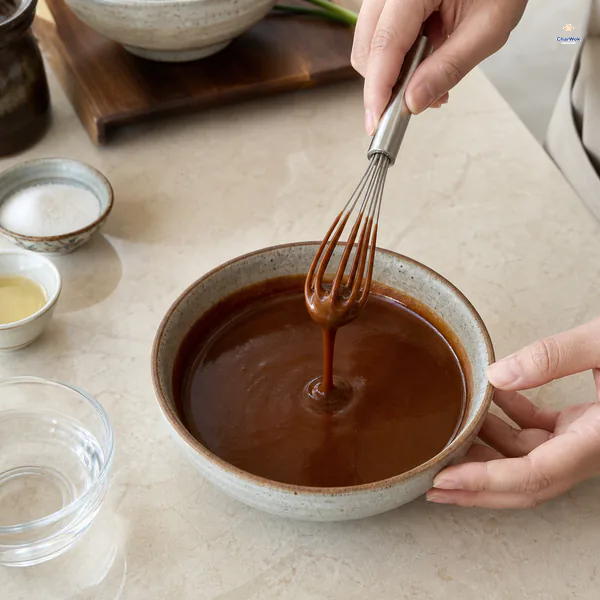 Deep brown sweet bean sauce is whisked with Shaoxing wine, sugar and water until smooth and thickly pourable