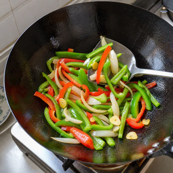 Long green and red bell pepper strips are flash-fried with onion and sliced garlic while remaining vivid and crisp