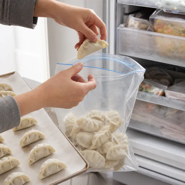 Firm individually frozen dumplings move from their tray into a clear unprinted airtight freezer bag