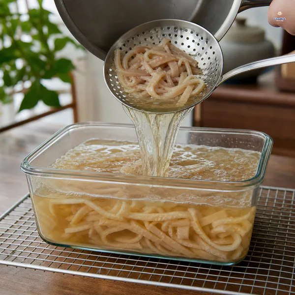 Clear collagen-rich broth and soft pork skin strips are poured into a plain glass container after every aromatic has been removed