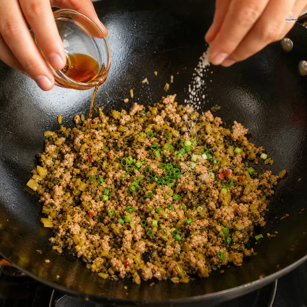 Sesame oil, a small pinch of sugar and white pepper, and green scallion tops finish the pork and pickled greens off the heat