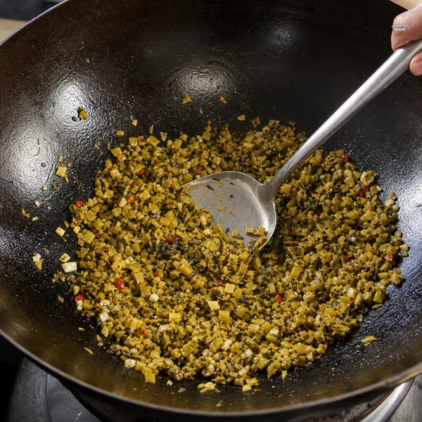 Finely chopped pickled mustard greens glisten in a dry wok with aromatic flecks and no meat or watery pool