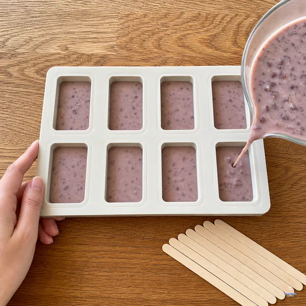 Bean-flecked popsicle base fills the last cavity of one eight-cavity mold while every surface remains visibly below its rim
