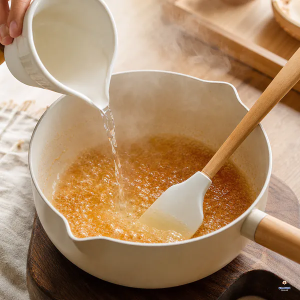 小杯热水沿离火锅边缓慢倒进琥珀糖液,泡沫受控留在锅内且双手远离蒸气