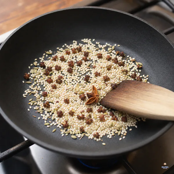 Sichuan peppercorns, half a star anise, white sesame, fennel seeds and fine salt are gently stirred in a dry black pan