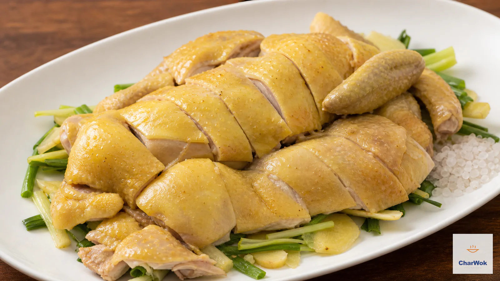 Pale-golden salt-baked chicken is carved into glossy skin-on pieces over ginger and scallion