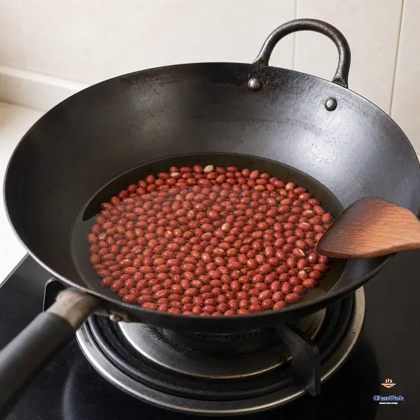Dry raw red-skin peanuts sit in a cold carbon-steel wok with clear oil reaching only halfway up them over an unlit burner