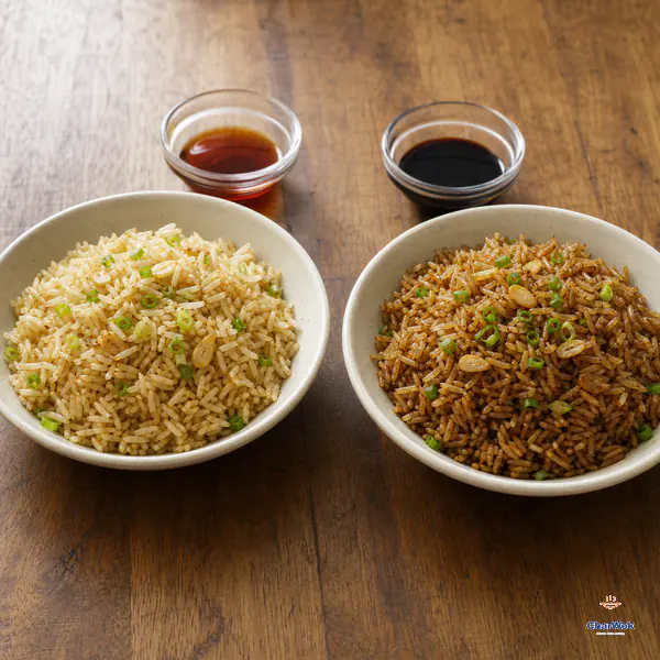 Two otherwise identical garlic-scallion fried rice bowls compare pale warm-gold grains with evenly coated mahogany-brown grains
