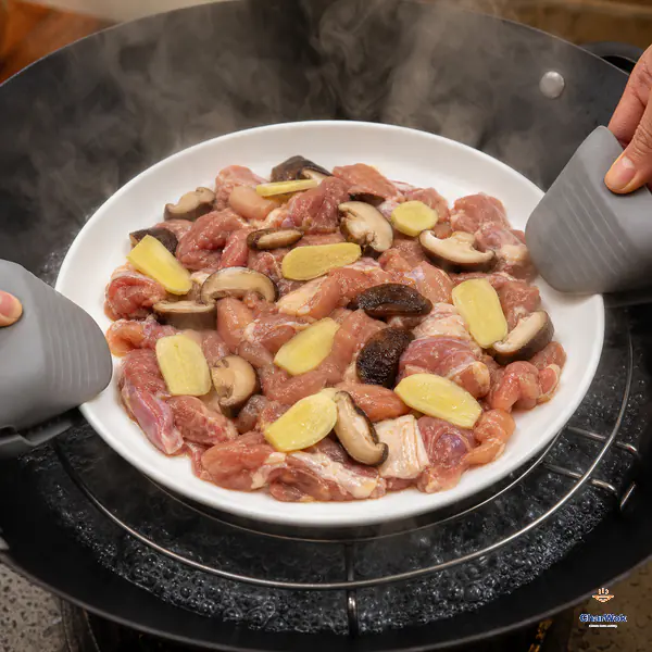 Heatproof grippers lower the level plate of raw chicken, shiitake mushrooms and ginger onto a steaming rack above visibly rolling boiling water