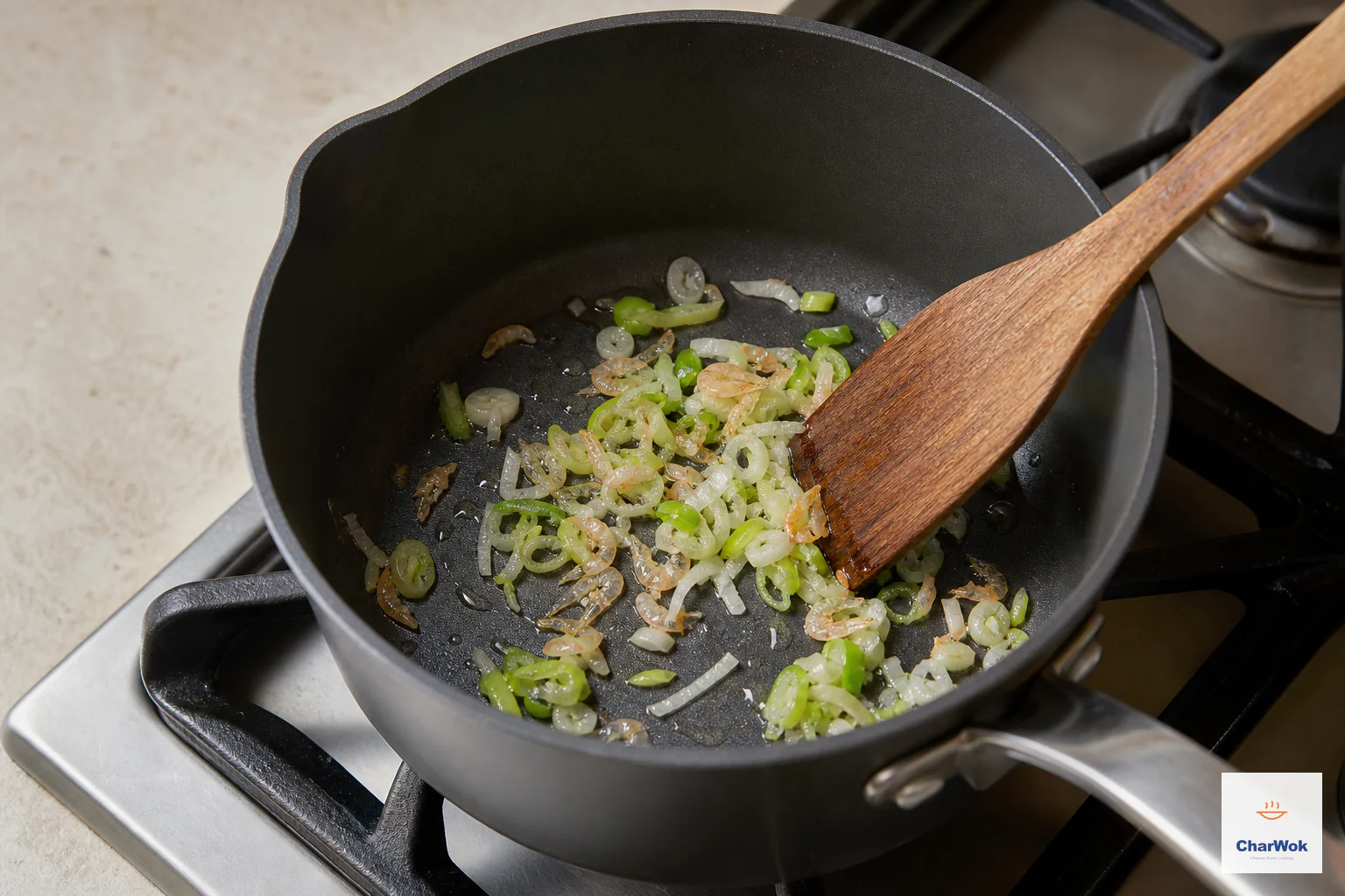 Scallion whites and a small spoonful of papery dried shrimp soften in a thin film of oil without browning