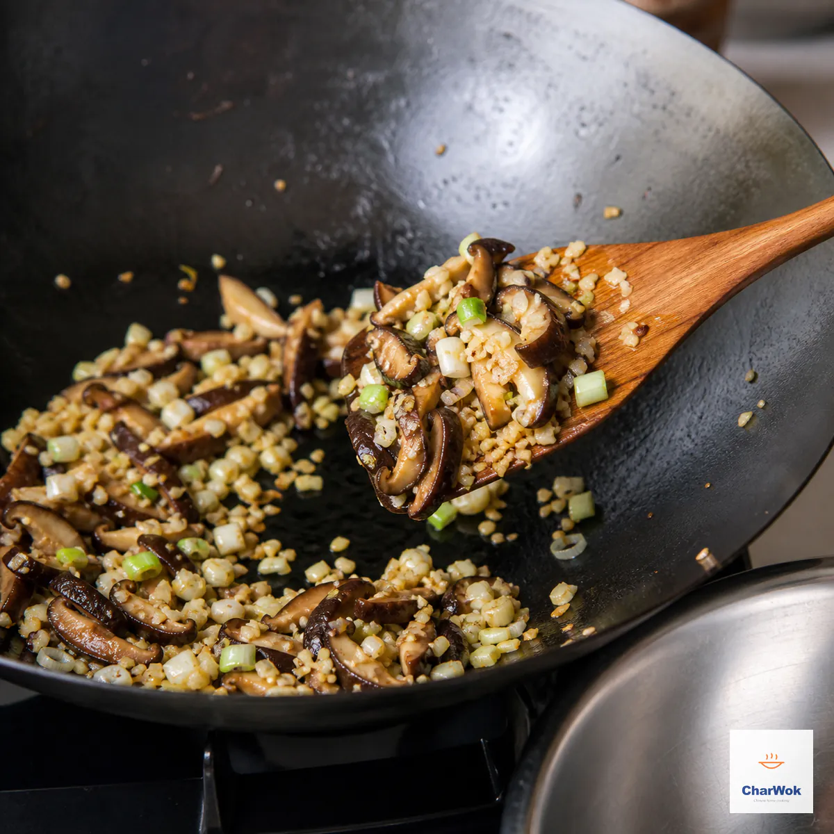 Minced garlic, pale scallion, and sliced shiitake sizzle in a wok until the mushroom edges curl and the moisture has evaporated
